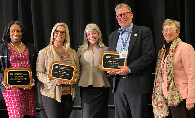 Three awardees holding awards pose with Marjorie Hass and Kathy Whatley