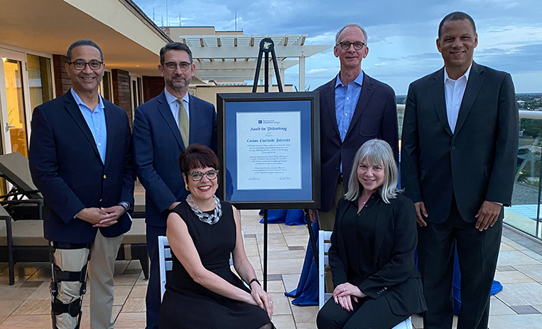 Canon representatives and others pose near framed award