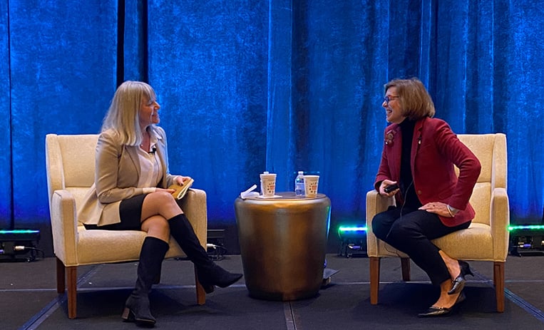 Mistick and Hass seated on chairs on stage