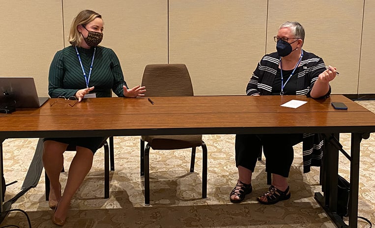 Two speakers seated at table