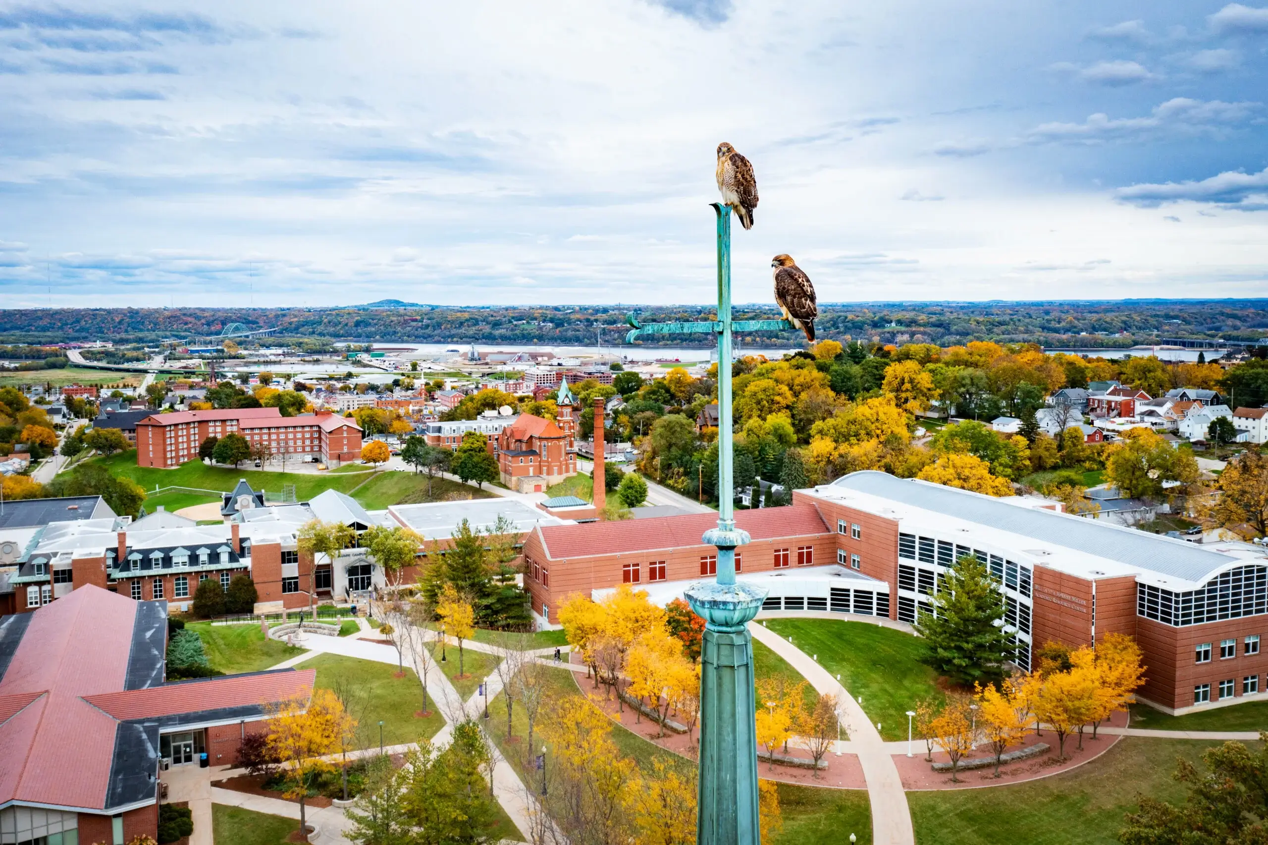 Two birds of prey resting on top of a cross belonging to the chapel of Loras College