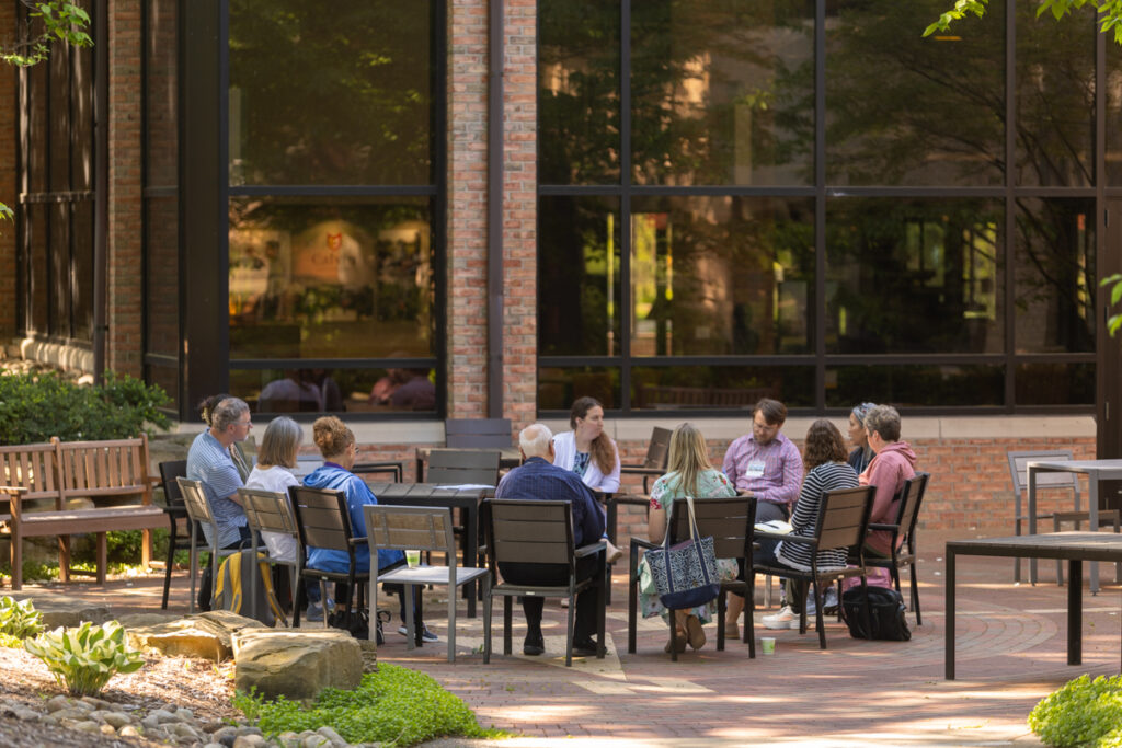 Participants in discussion at tables out in a courtyard