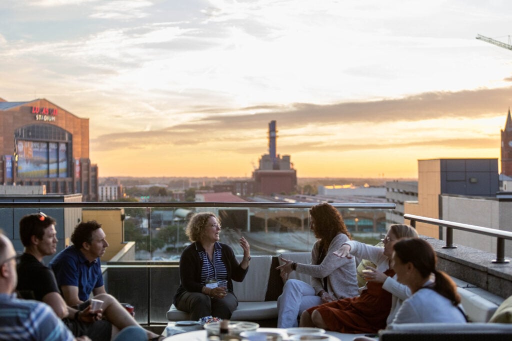 Seminar participants leisurely sit outside the Alexander as the sun sets behind them