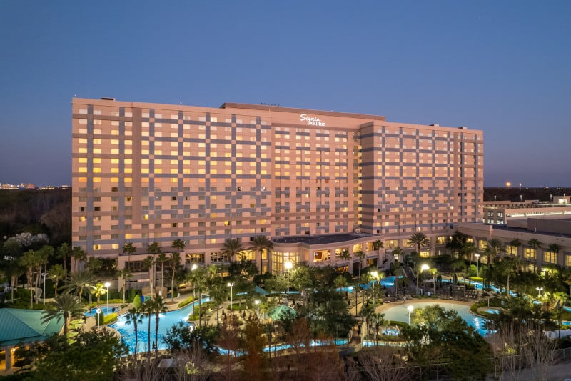 Exterior view of Signia by Hilton Orlando at night with illuminated pool in foreground