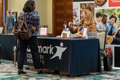 Sponsor from Aramark seated at booth speaking with participant