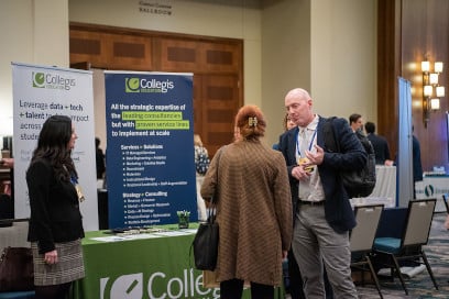 Two sponsors from Collegis speaking with a participant in front of their booth