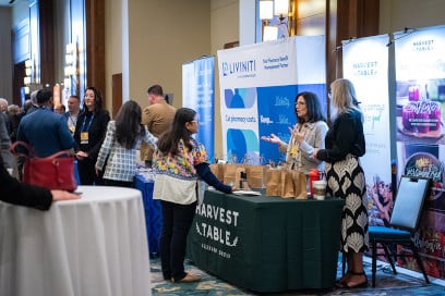 Two sponsors from Harvest Table speak with a participant at their booth