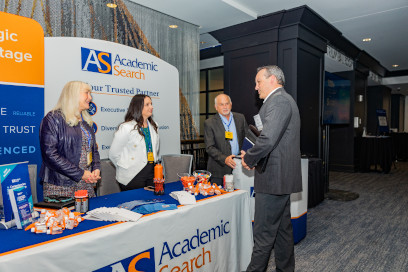 Three sponsors from Academic Search speak with a participant at their booth