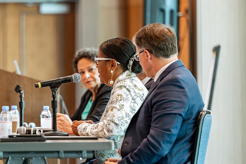 Three presenters speak while seated at head table