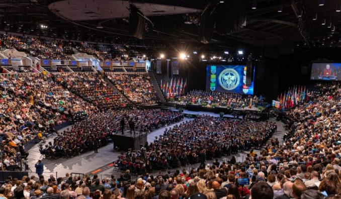 Indoor arena full with students and guests for graduation ceremony