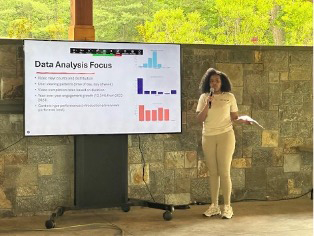 Student stands with microphone next to screen with slide that reads Data Analysis Focus