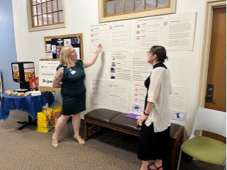 Two students present while gesturing to their poster presentation