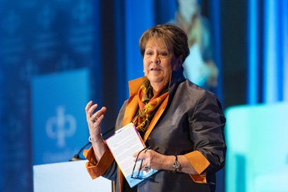 Presenter speaking from podium holding notes