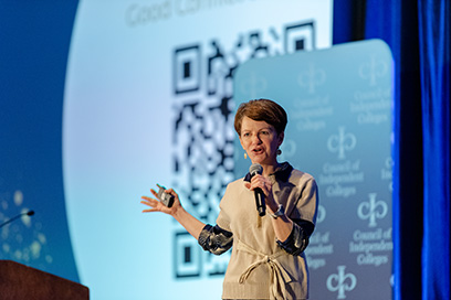Plenary speaker presents while standing on stage holding slide advancer and microphone