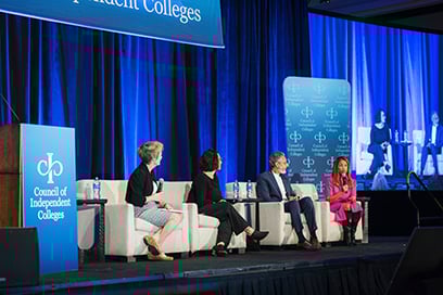 Four plenary speakers seated on chairs on stage