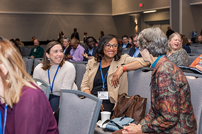 Three participants speak before a plenary session begins