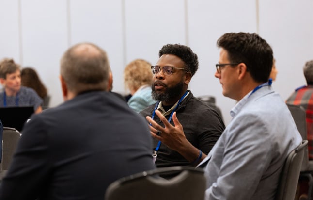 Participants seated at roundtables speaking with each other