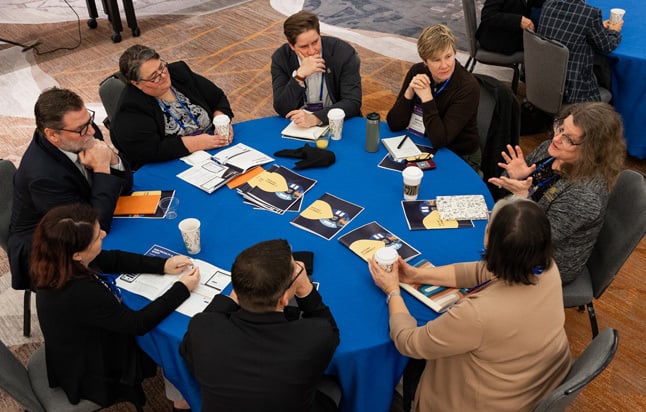 8 participants seated at a roundtable for a discussion topic