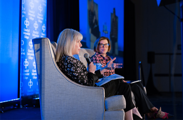 Marjorie Hass and Barbara Mistick seated in chairs on stage during closing plenary session