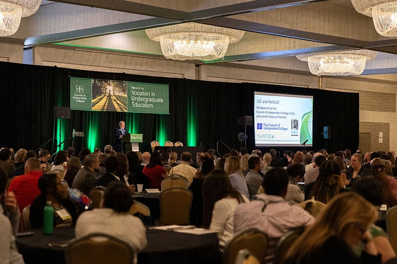 David Cunningham presents on stage from podium before seated participants