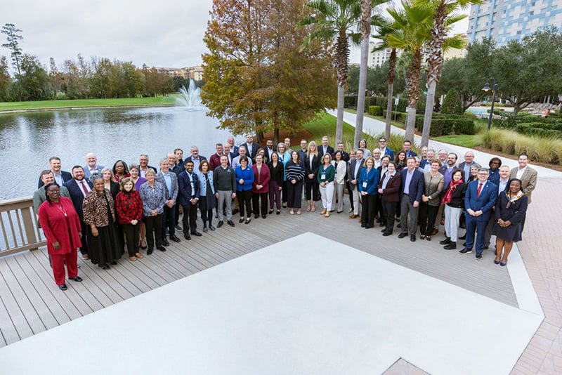 Group aerial photo of new presidents standing outside in front of pond