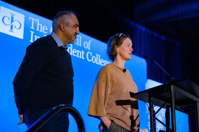 Kia Afcari and Emiliana Simon-Thomas stand on stage at podium