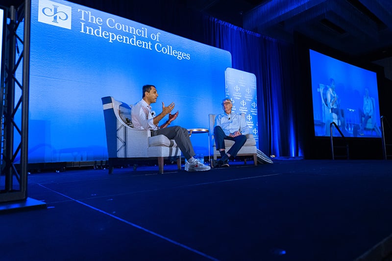 Eboo Patel and Grant Cornwell sit on chair on stage