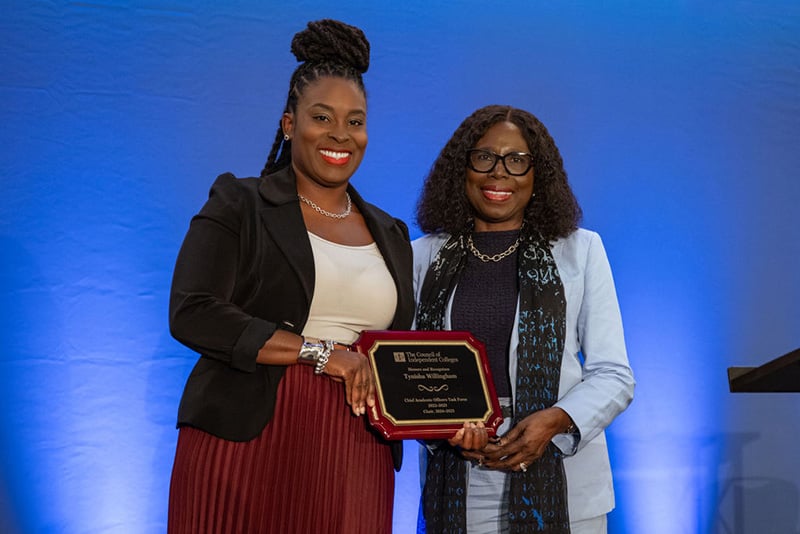 Tynisha Willingham holds award and poses with Titi Ufomata