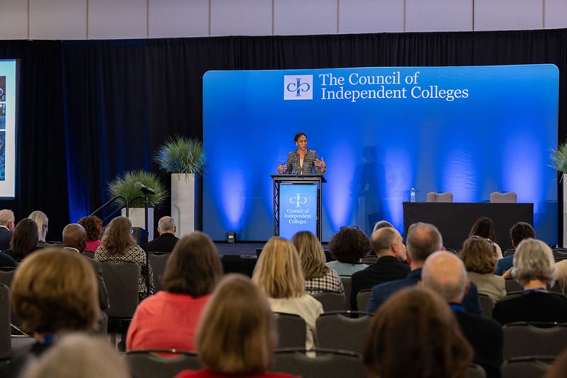 Amelia Parnell presents from podium on stage before seated audience