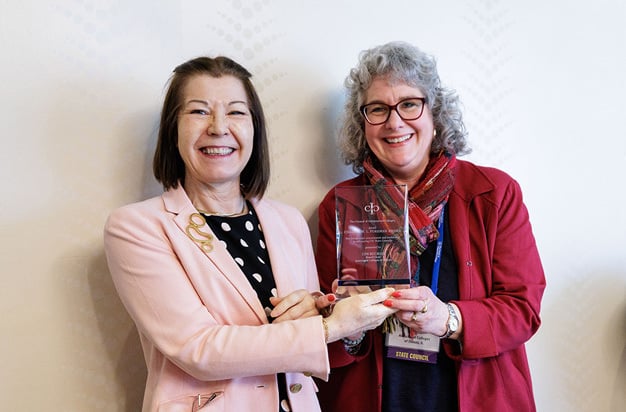 Two participants stand holding crystal award