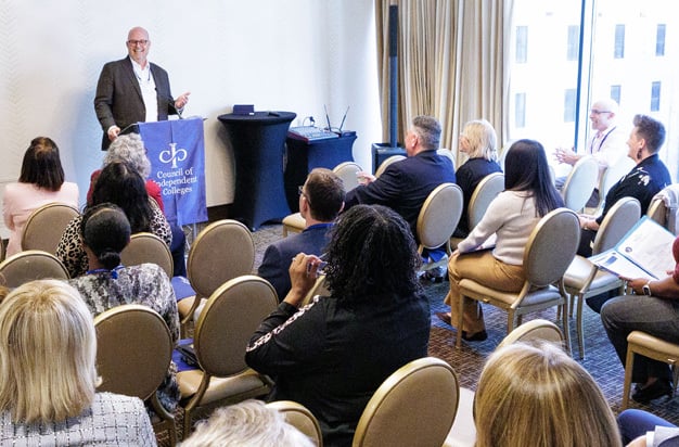 Presenter speaks from podium in front of seated participants