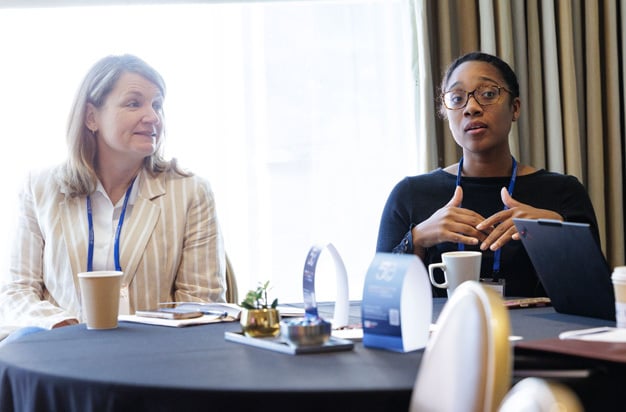 Two participants speaking while seated at a roundtable