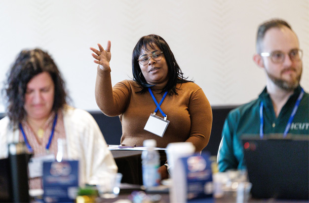 Three seated participants during a session; one is speaking to the group