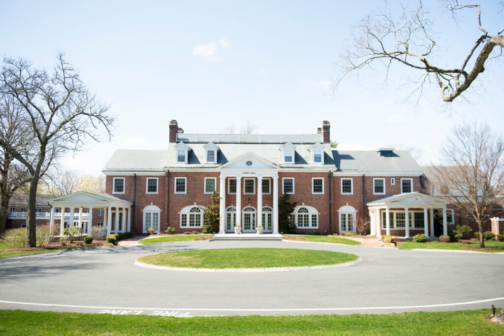 A red brick building with white pillars on Bay Path University's campus.